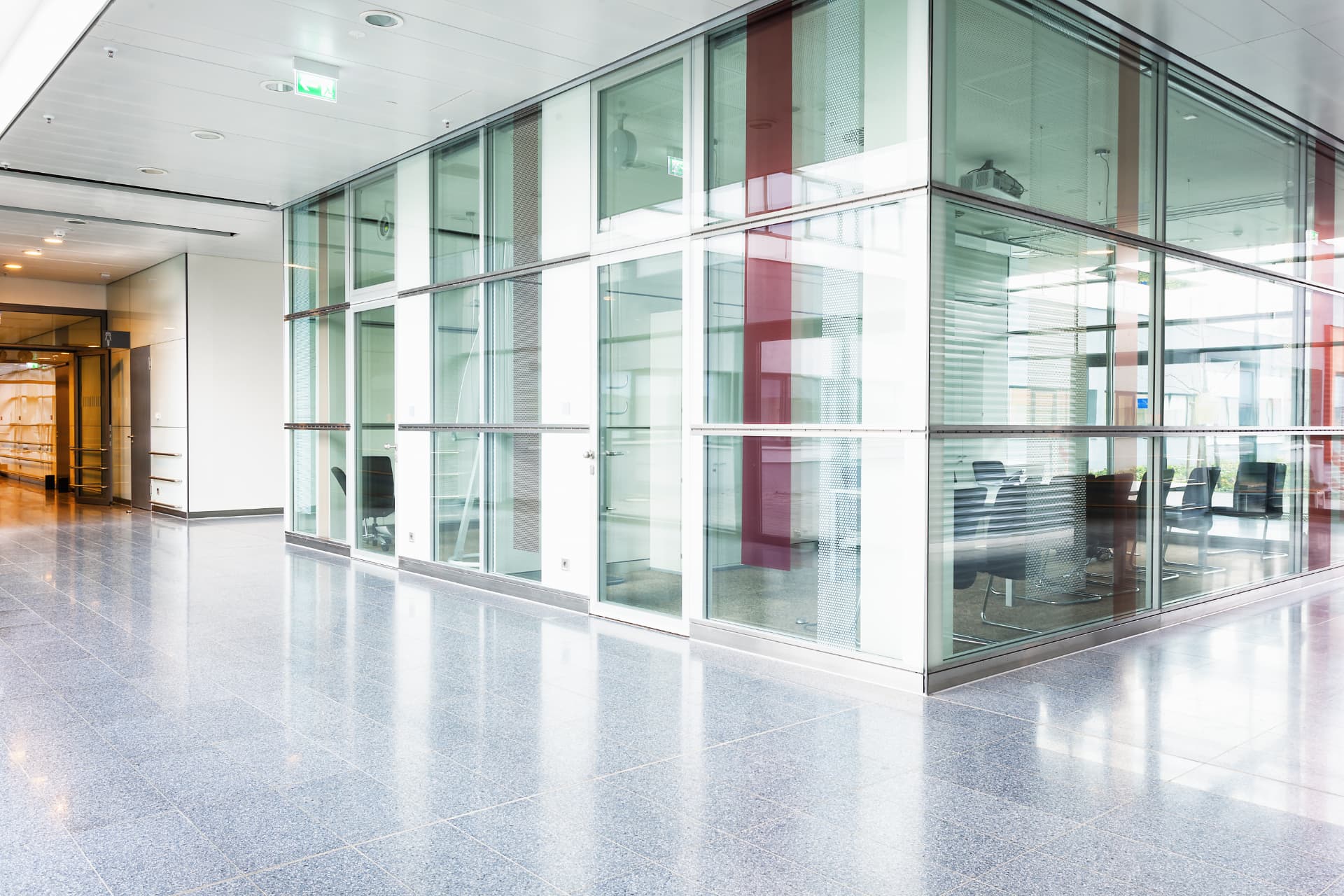 Bright glass-walled office corridor with meeting rooms